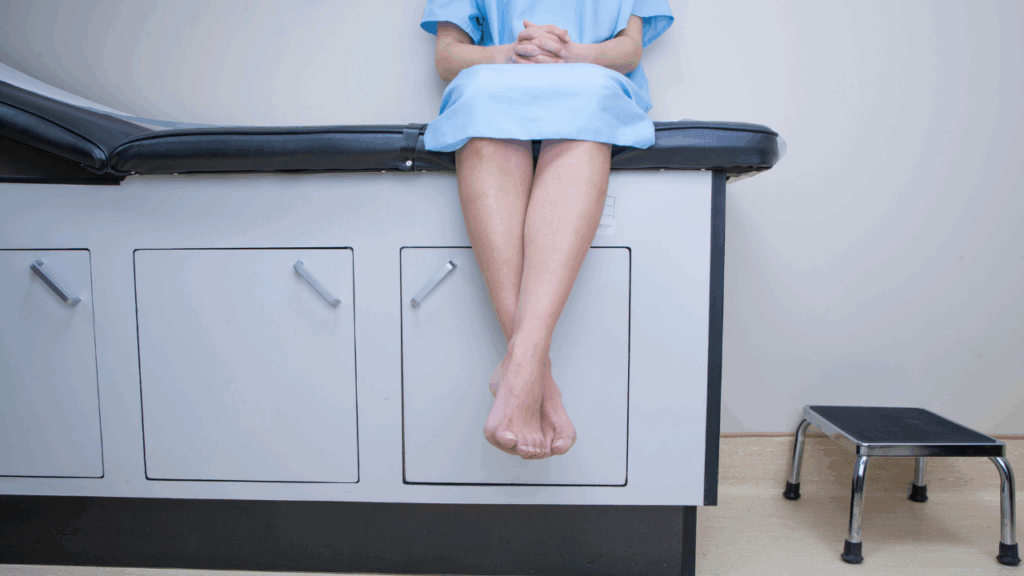 female patient at doctor's office waiting on an examination table in gown